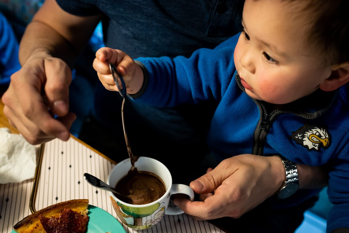 Famililienreportage. Ein kleiner Junge schaut sich sein Spiegelbild in einem Löffel an.