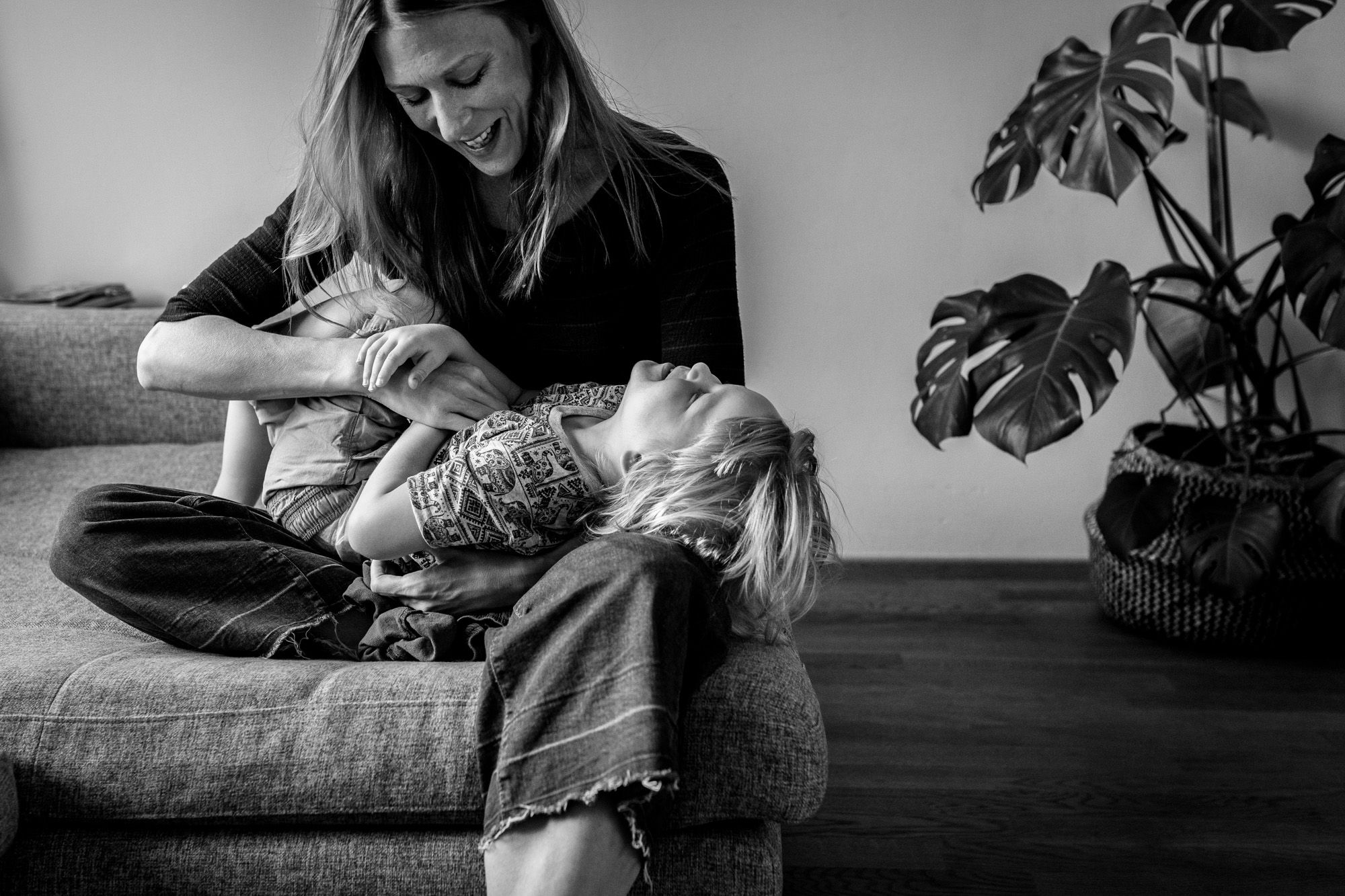 Mutter kitzelt ihren Sohn, beide lachen.