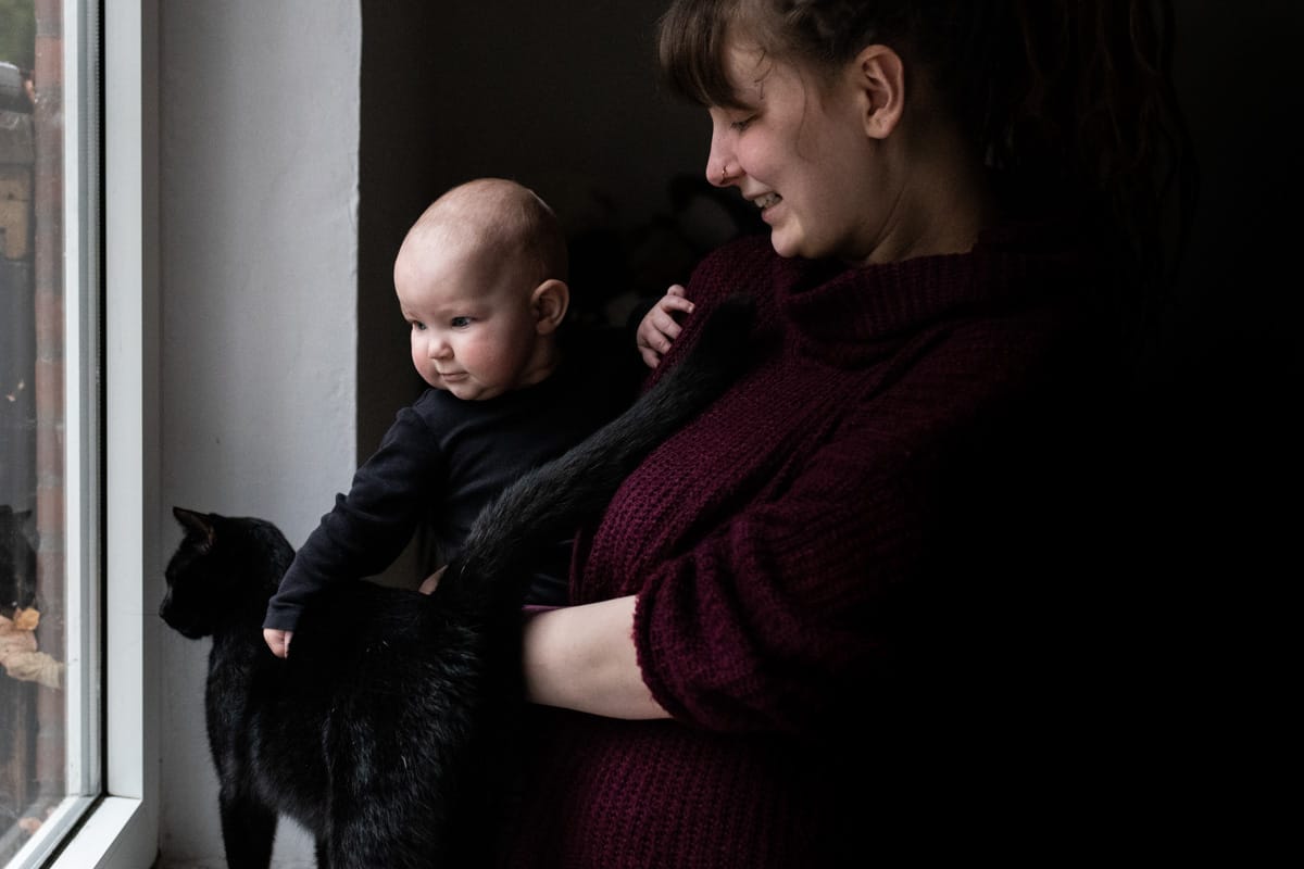 Mutter mit Baby und Katze am Fenster