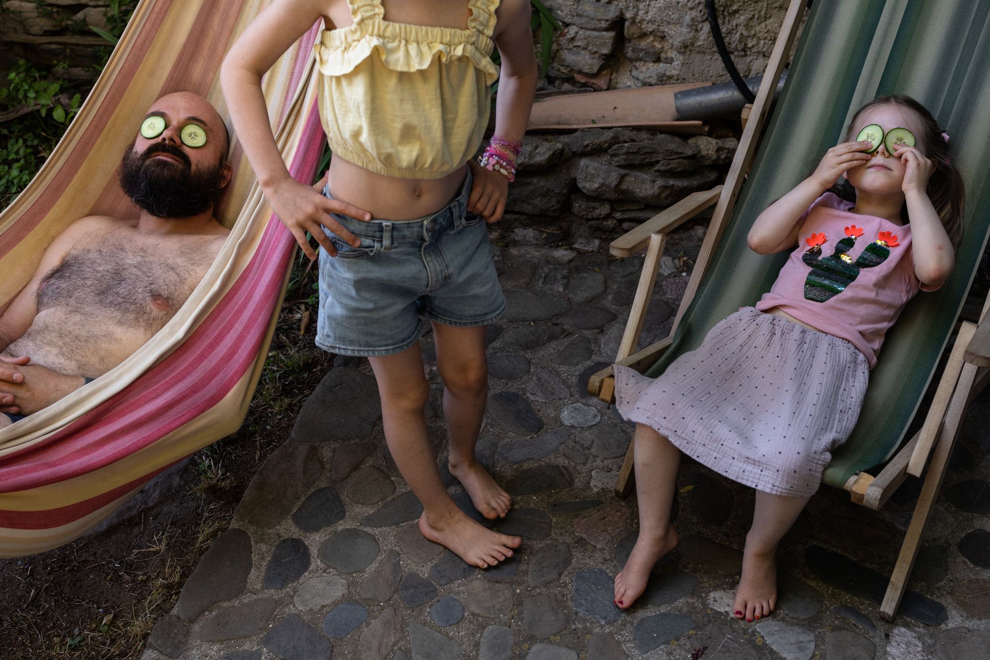 Familienreportage: Vater mit seinen Kindern antspannen mit Gurkenscheiben auf den Augen