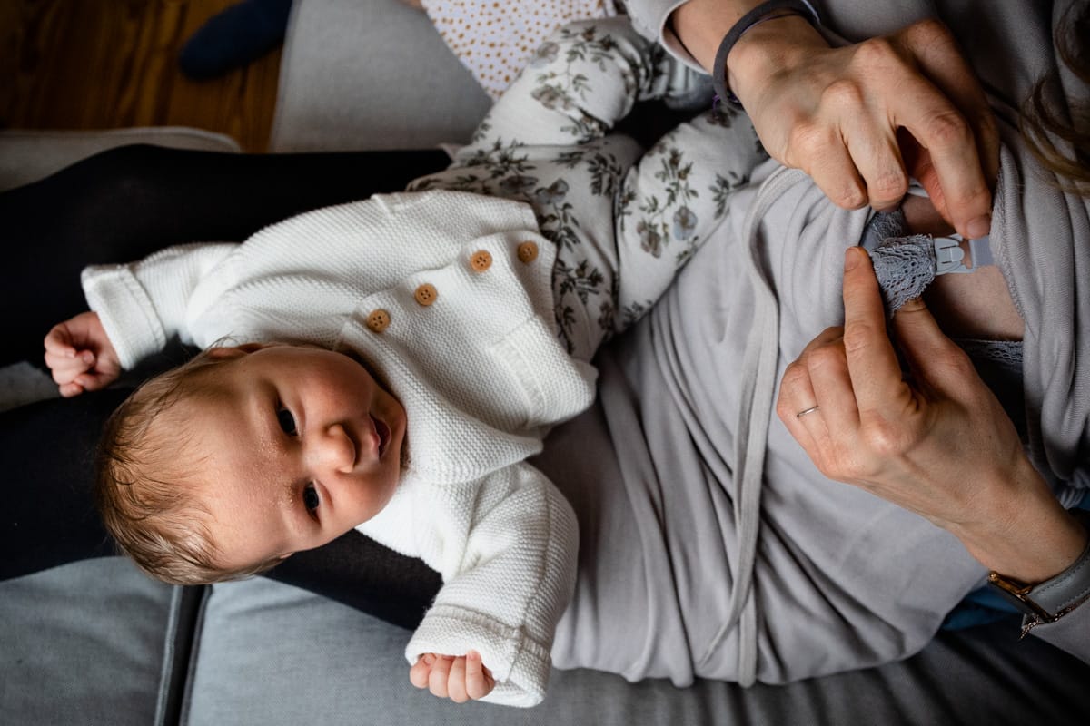 Stillen. Mutter hat das Baby auf dem Schoß und bereitet sich auf das Stillen vor.