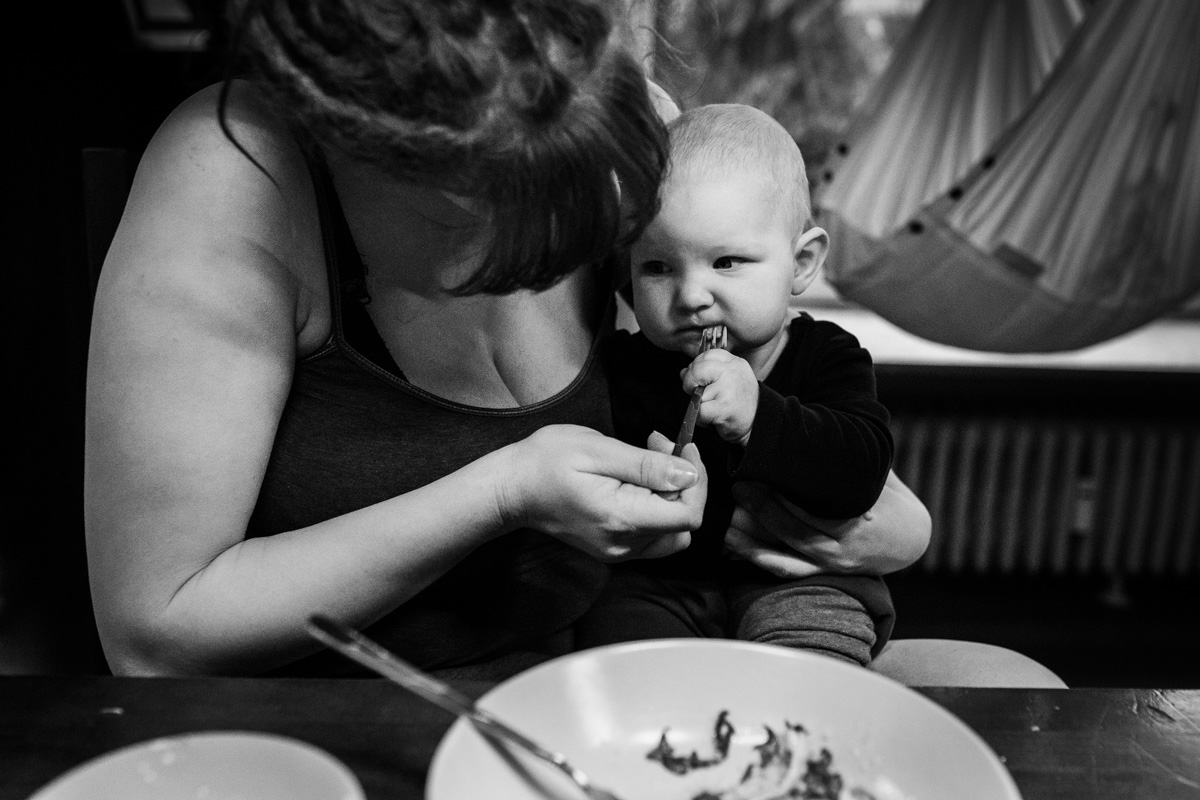 Ein Baby sitzt auf dem Schoß seiner Mutter und wird gefüttert