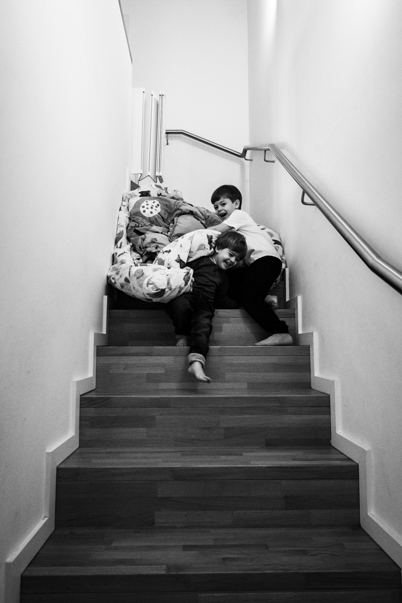 Kinder spielen auf einer Treppe mit einer Decke und lachen.