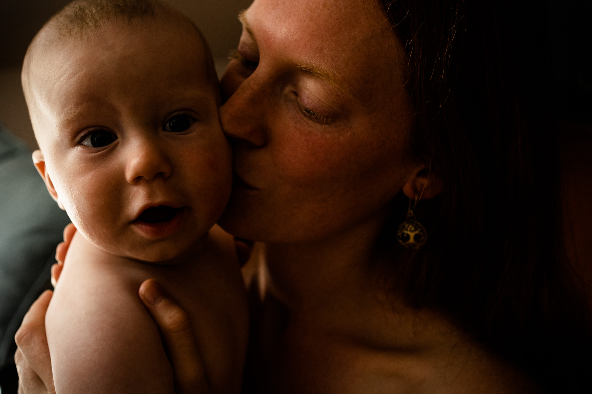 Mama küsst ihr Baby und hält ihre Augen genüsslich geschlossen